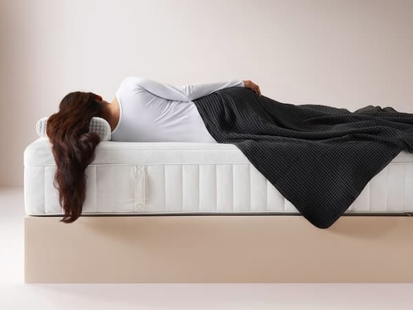 Eine Frau liegt seitlich auf einer IKEA Matratze und schläft.