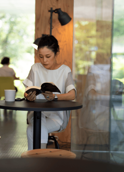 Eine Frau liest in einem Café an einem Tisch.