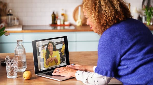 Eine Frau mit brauen lockigen Haaren sieht hat einen Videocall mit der IKEA Küchenabteilung.