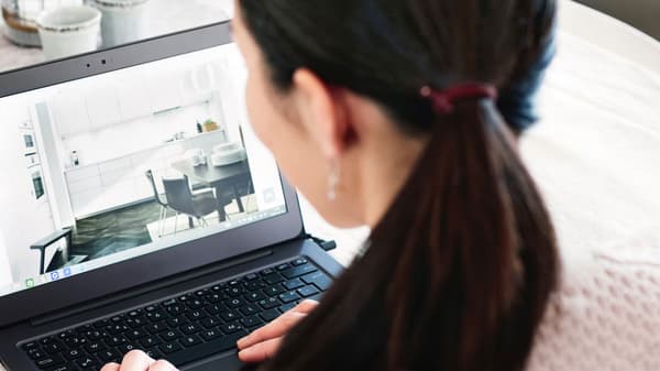 Eine Frau mit dunklen Haaren sitzt an einem Laptop und sieht sich Küchenbeispiele an.