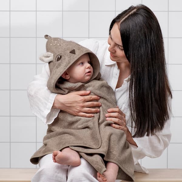 Eine Frau mit einem Baby in einem TROLLDOM Kapuzenhandtuch im Badezimmer.
