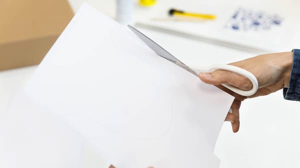 Eine Frau schneidet ein weißes Papier mit einer Schere
