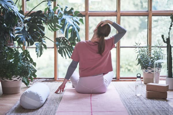 Eine Frau sitzt auf dem Boden und macht Yoga.