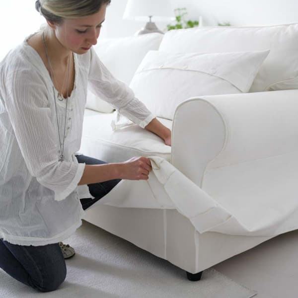 Eine Frau wechselt den Bezug an einem EKTORP Sofa. 
