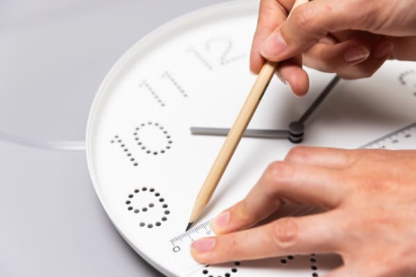 Eine Frau zeichnet etwas auf eine Uhr.