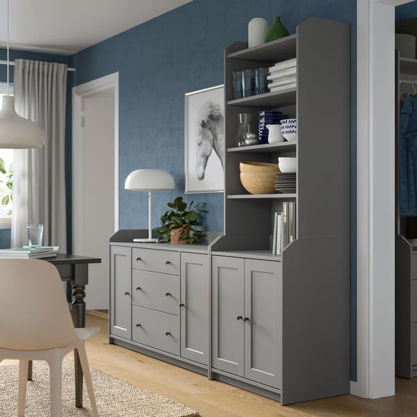 Eine graue HAUGA Kombination aus einem Sideboard neben einem Hochschrank steht an einer Wohnzimmerwand.