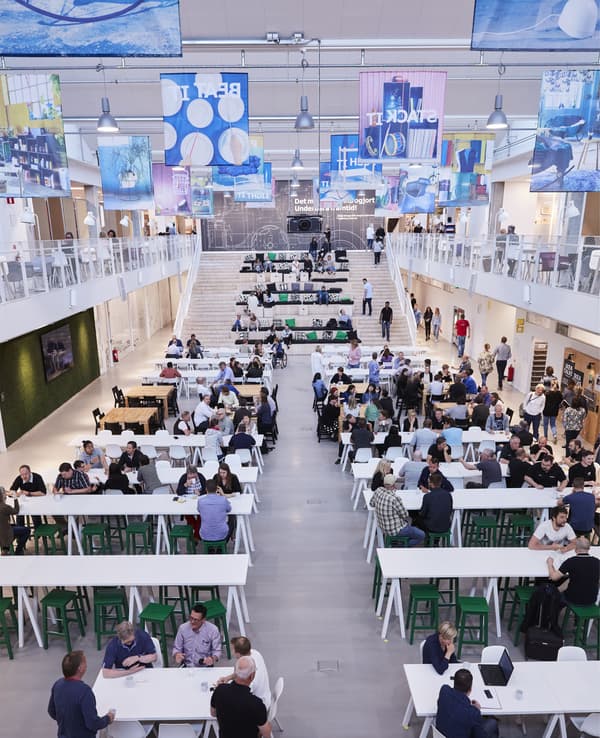 Eine grosse Halle, in der Menschen allein oder in Gruppen arbeiten, auf Bänken, Treppenstufen und an Tischen