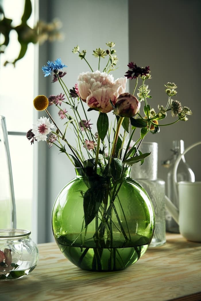eine grüne Blumenvase mit Blumen darin