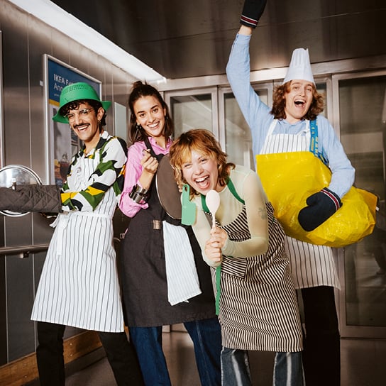 Eine Gruppe junger Menschen mit Kochschürzen in ausgelassener Stimmung.