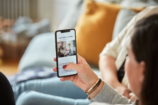 Eine Hand hält ein Smartphone hoch, das ein IKEA Family Profil anzeigt. 