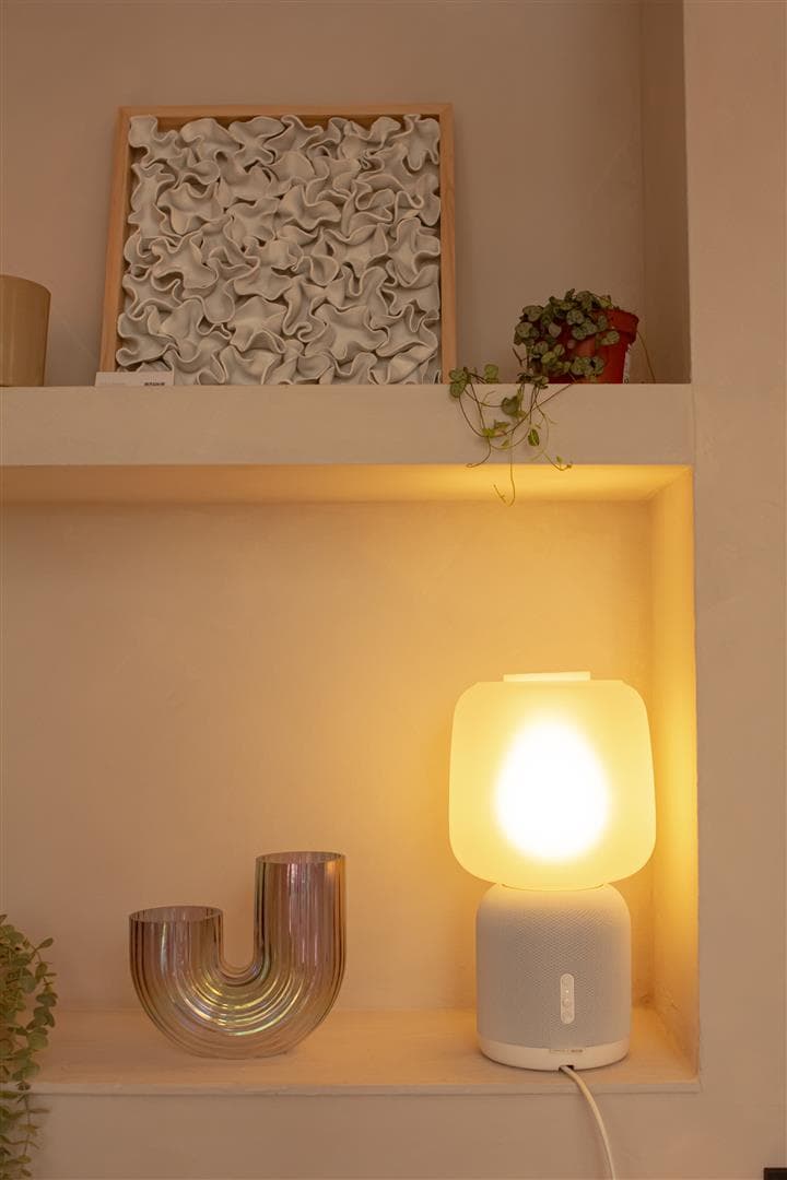 Eine helle Lampe steht in einem weißen Regal.