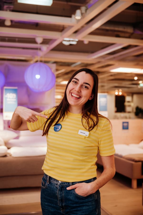 Eine IKEA Mitarbeiter:in zeigt auf ihren Schlafexpert:innen Button.