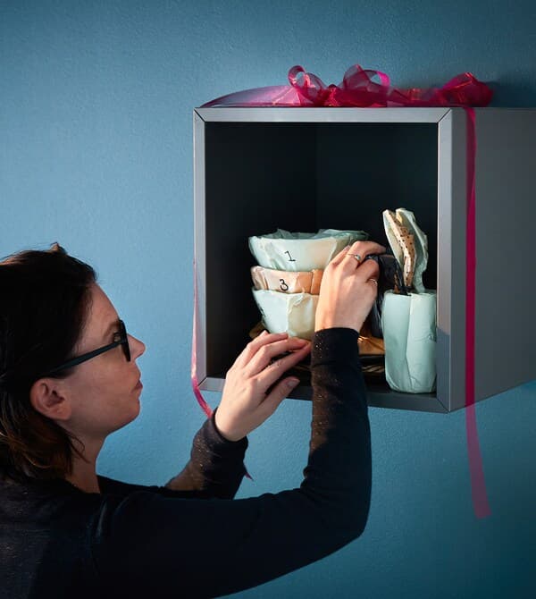 Eine Inneneinrichterin arrangiert verpacktes Geschirr in einem Regal