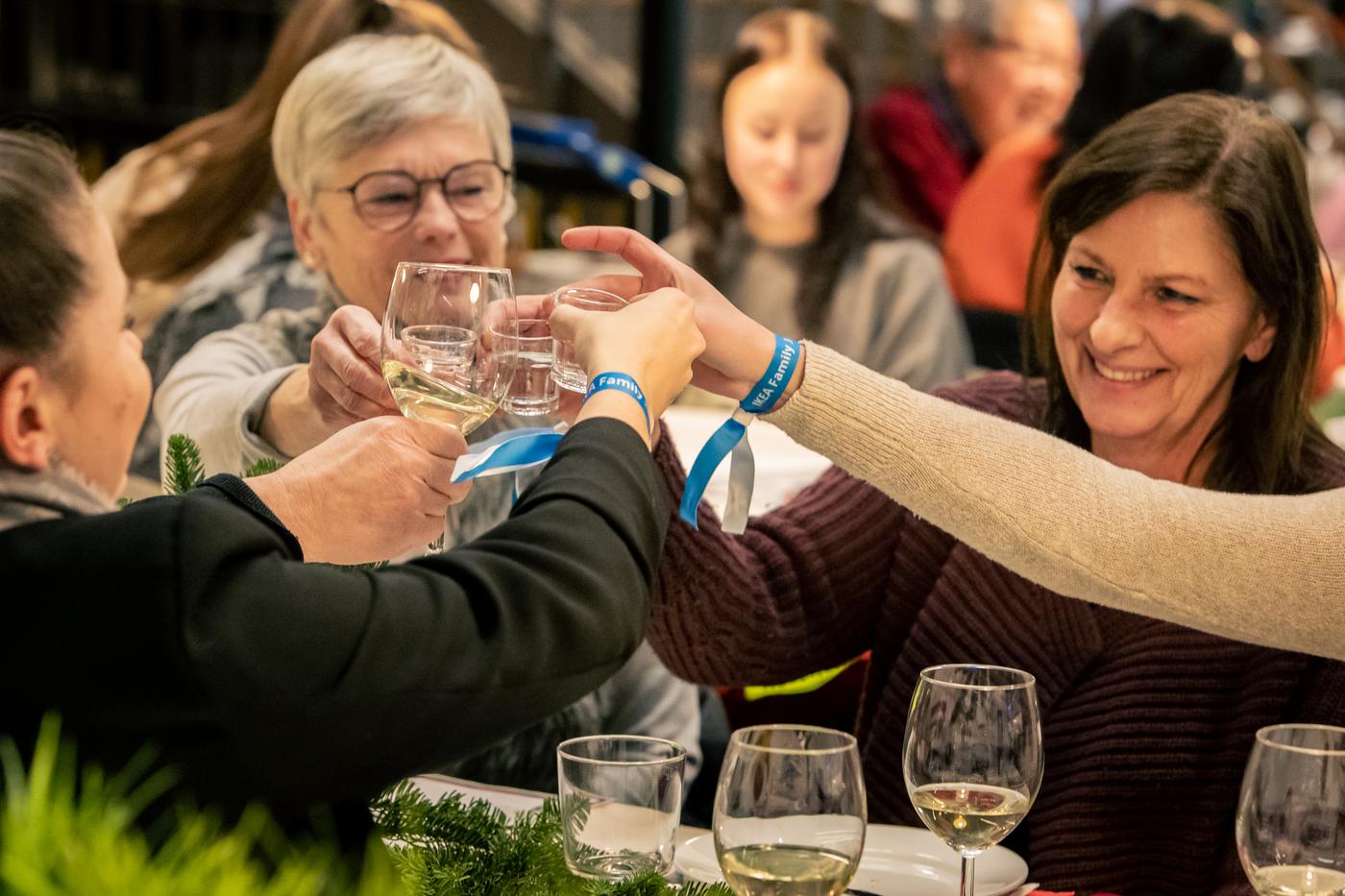 Eine kleine Personengruppe sitzt an einem Tisch und stößt an.