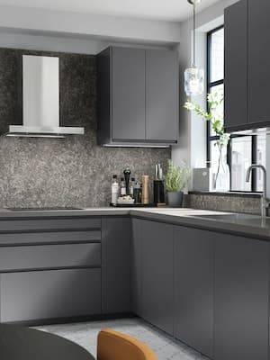 Eine Küche mit grauen Schränken und Küchenfronten sowie einer Dunstabzugshaube aus Edelstahl.
