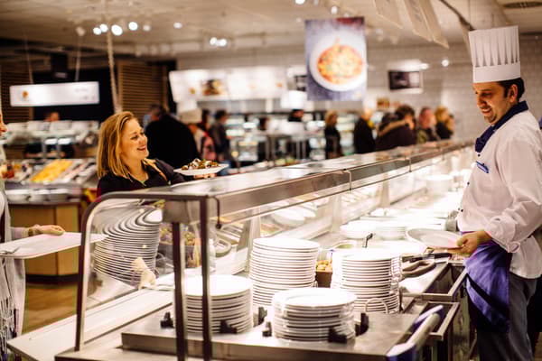Eine Kundin bestellt ihr Essen beim IKEA Mitarbeiter im IKEA Restaurant.