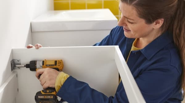 Eine Mitarbeiterin des IKEA Badinstallationsservice montiert ein Möbelstück im Badezimmer.