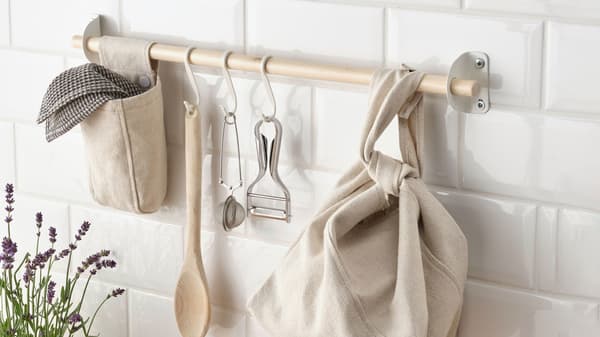 Eine NEREBY Wandhalterungsstange aus Holz mit NEREBY Taschen und Haken, an denen Küchenutensilien hängen.