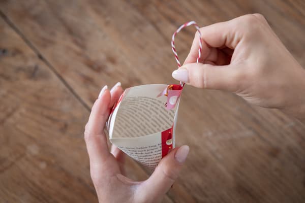 Eine Person befestigt eine Lasche an einer selbstgemachten Geschenktüte.