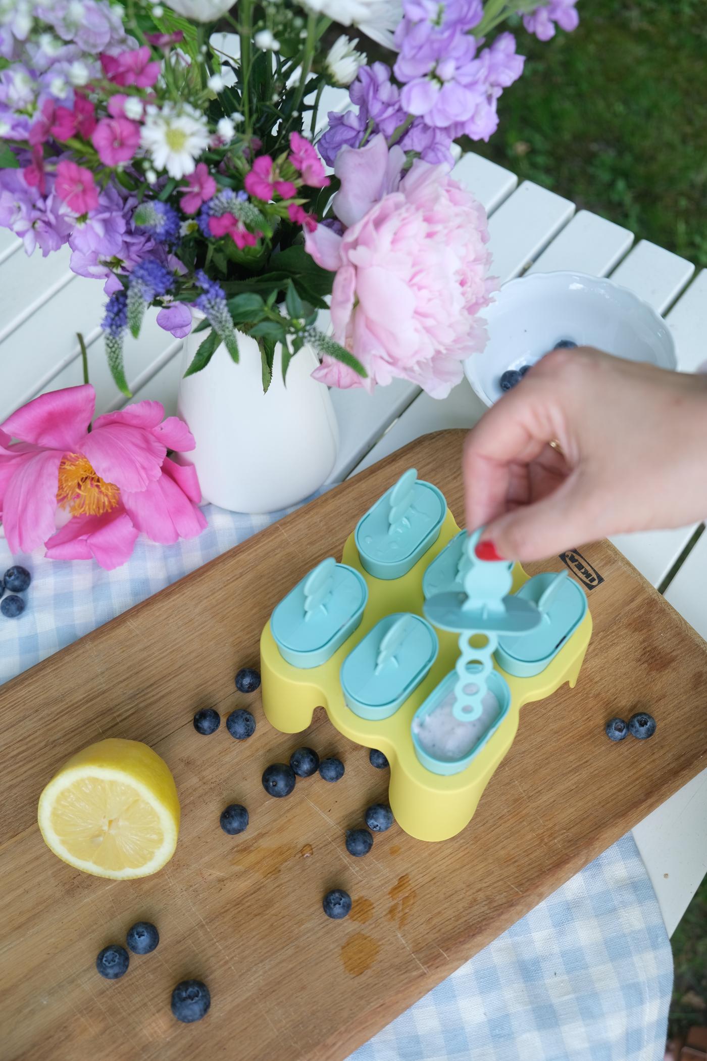 Eine Person befüllt Eisförmchen für Blaubeer-Eis.