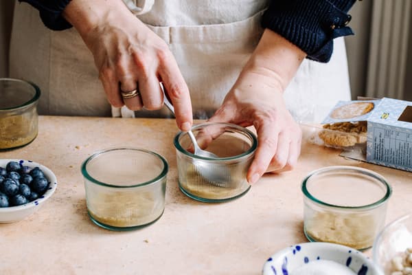 Eine Person bereitet 4 Gläser für das Dessert vor.