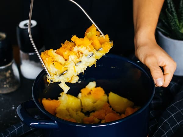 Eine Person bereitet Kürbis-Kartoffel-Stampf für das Rezept Plantbullar in Pfifferling-Rahm-Sauce zu.