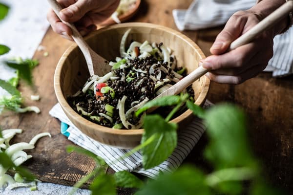 Eine Person bereitet Linsen-Fenchel-Salat in einer Salatschüssel zu.