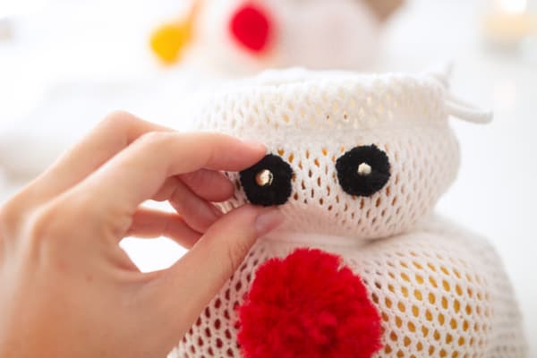 Eine Person bringt Augen an dem DIY Rentier an.