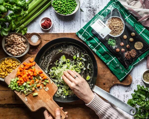 Eine Person dünstet die Zutaten für veganen Hack-Pie in einer Pfanne.