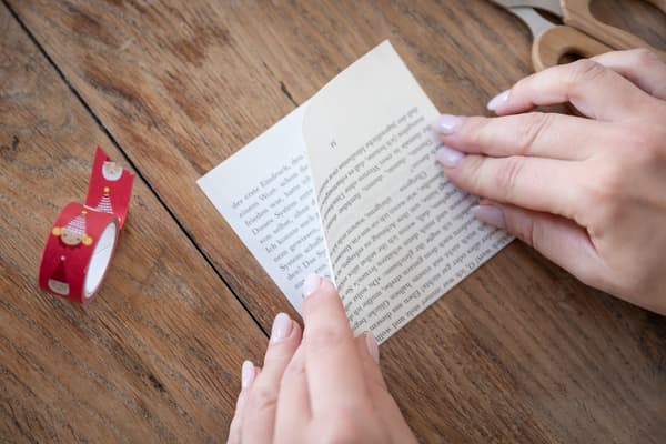 Eine Person faltet ein Stück Papier.