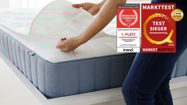 Eine Person gibt einen Matratzenschoner auf eine Matratze. Am Bild 2 Testsieger Logos. Auf den Logos steht folgender Text: 