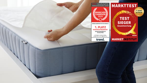 Eine Person gibt einen Matratzenschoner auf eine Matratze. Am Bild 2 Testsieger Logos. Auf den Logos steht folgender Text: 