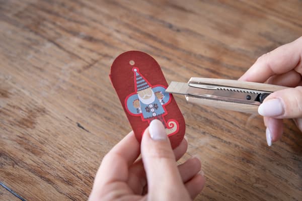 Eine Person hält ein Messer und einen Teil einer Geschenkpackung in der Hand.