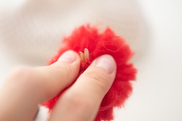 Eine Person hält ein rotes Stoffknäuel in der Hand.