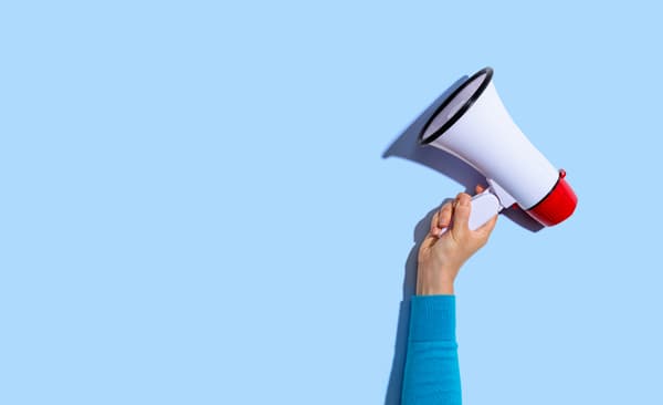 Eine Person hält ein weißes Megaphone in die Luft.