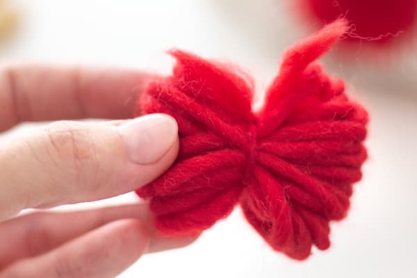 Eine Person hat aus rotem Garn eine Schleife gebunden.
