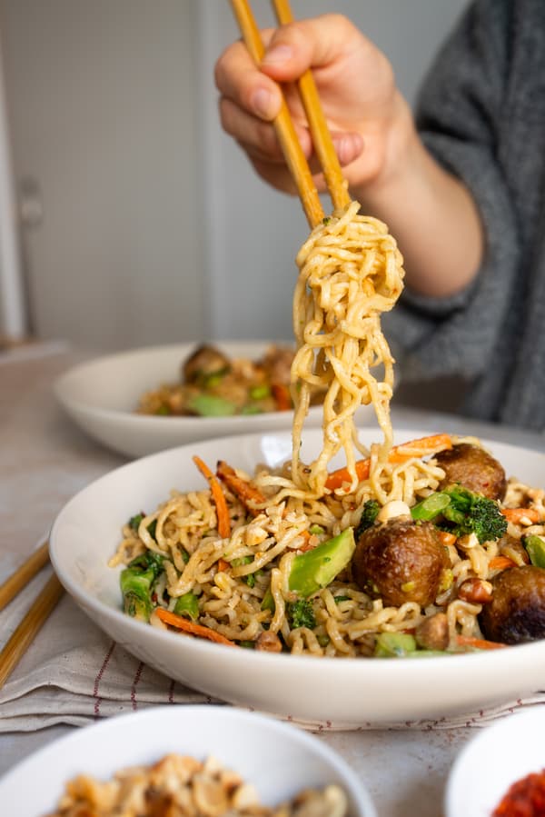 Eine Person isst vegane Erdnuss-Nudeln mit Stäbchen
