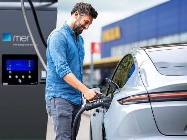 Eine Person lädt ein Elektroauto an einer IKEA Ladestation.