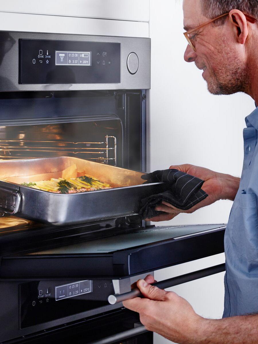 Eine Person nimmt ein Gericht aus einem Backofen.