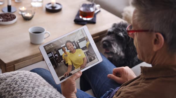 Eine Person schaut auf ein Tablet, darauf ist ein IKEA Mitarbeiterin zu sehen.