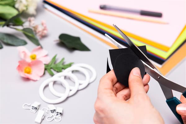 Eine Person schneidet einen Kreis aus einem schwarzen Papier aus.