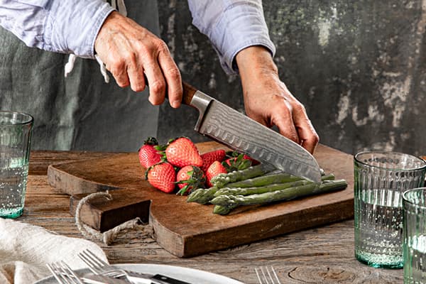 Eine Person schneidet frischen Spargel und Erdbeeren für das Rezept 