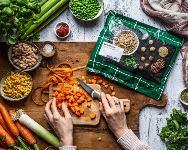 Eine Person schneidet Möhren und bereitet weitere Zutaten für veganen Hack-Pie vor.