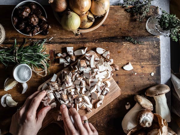 Eine Person schneidet Pilze für das Rezept PLANTBULLAR mit Pilz-Maronen-Ragout.