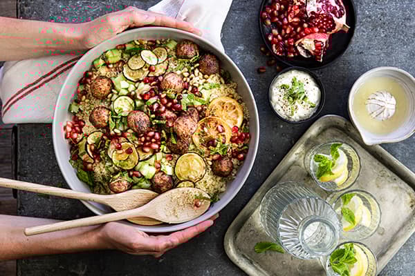 Eine Person serviert eine Schüssel mit Couscous Salat mit Minze.