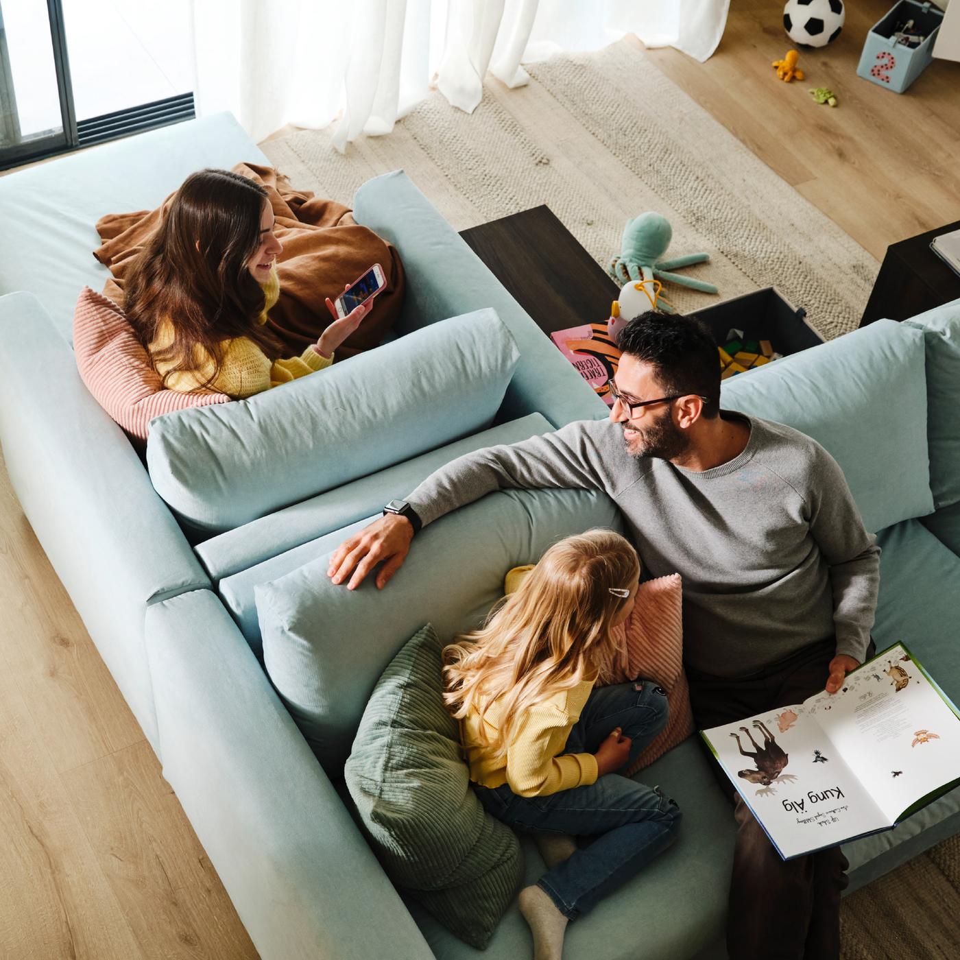Eine Person und ein Kind sitzen auf einem VIMLE 3er-Sofa, das Rücken an Rücken mit einer VIMLE Récamiere steht. Auf dieser sitzt eine weitere Person.