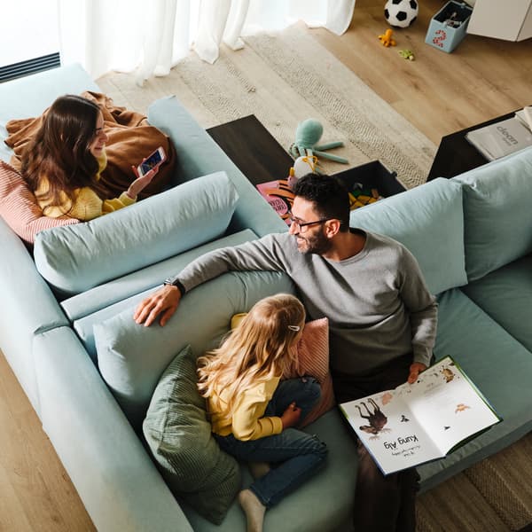 Eine Person und ein Kind sitzen auf einem VIMLE 3er-Sofa, das Rücken an Rücken mit einer VIMLE Récamiere steht. Auf dieser sitzt eine weitere Person.