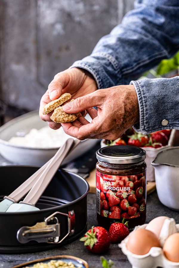 Eine Person zerbröselt Haferkekse für den Kuchenboden des Käsekuchen mit Haferkeksboden.