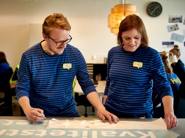 Eine Reihe ineinandergeschobener IKEA Einkaufswagen wird durch ein IKEA Einrichtungshaus geschoben.