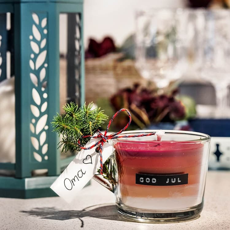 Eine rote Kerze mit einem kleinen Zettel auf der Seite steht auf einem Tisch.